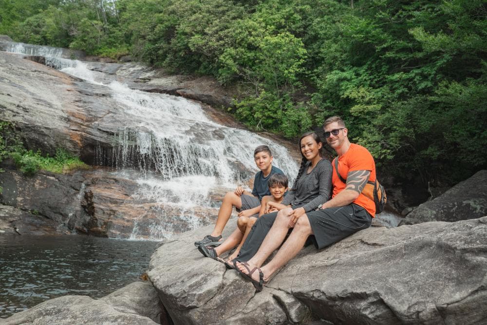 A family enjoys a stunning waterfall in the Blue Ridge Mountains near Asheville, NC A family enjoys a stunning waterfall in the Blue Ridge Mountains near Asheville, NC