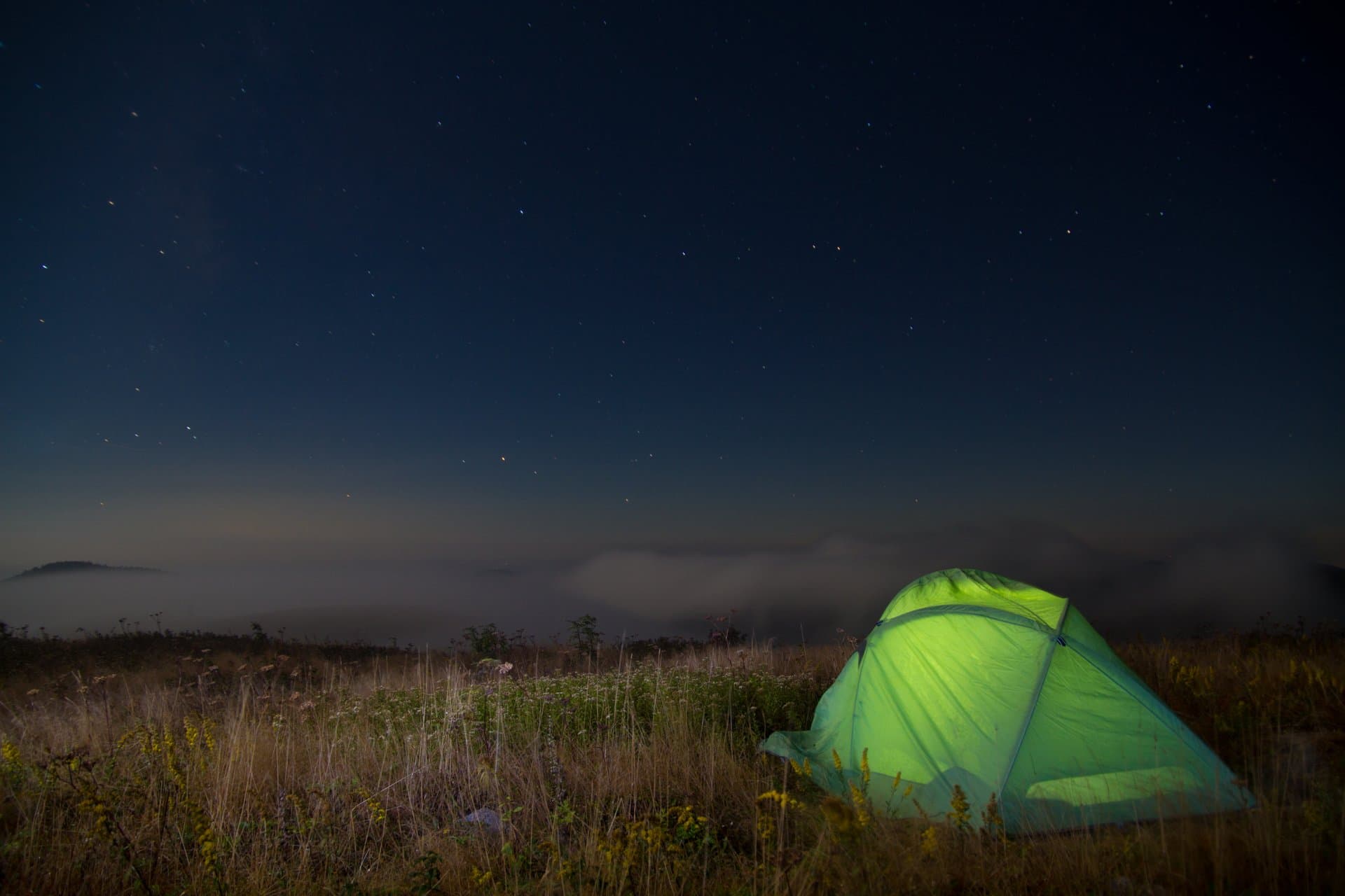 Green tent in field in at night at campground Green tent in field in at night at campground